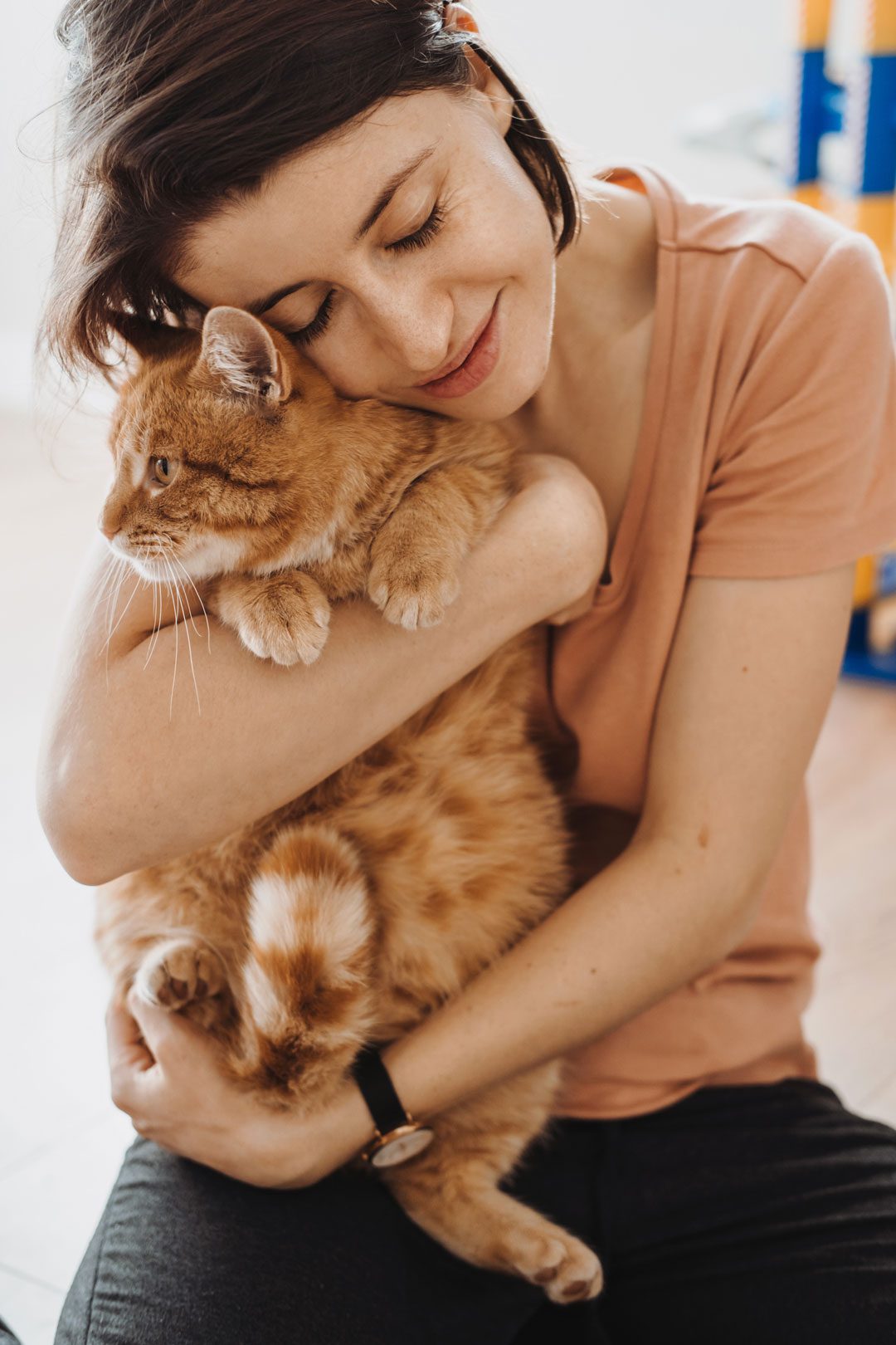 woman smiling and embracing orange cat